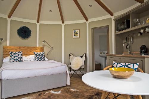 a bedroom with a bed and a table and a kitchen at Nether Farm Roundhouses - Henmore Water & Sturston Winds with hot tubs - Bradley Wood no hot tub in Ashbourne