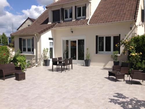 eine Terrasse mit Stühlen und einem Tisch vor einem Haus in der Unterkunft Roissy Chambres in Roissy-en-France