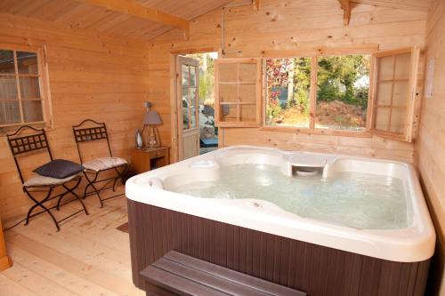 eine Whirlpool-Badewanne in einem Blockhaus in der Unterkunft Manoir Desnachez in Taupont