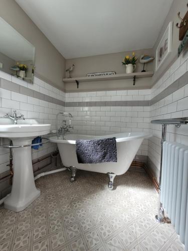 a bathroom with a white tub and a sink at Charming 2-Bed Cottage on outskirts of Beverley in Beverley