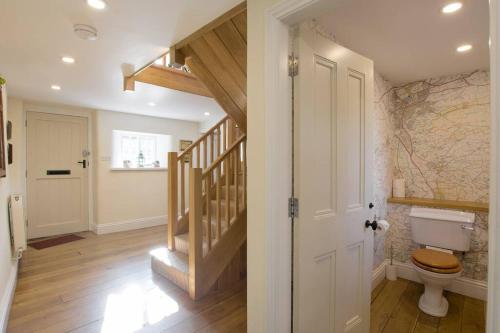 a bathroom with a toilet and a hallway with a staircase at Higher Scarcliffe at Broughton Sanctuary in Skipton
