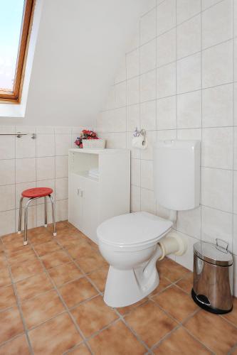 a bathroom with a white toilet and a red stool at Ferienwohnungen im Haus Herrmann in Neuharlingersiel