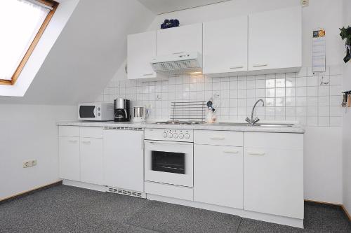 a white kitchen with white cabinets and a sink at Ferienwohnungen im Haus Herrmann in Neuharlingersiel
