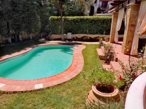 a swimming pool with a brick walkway around it at Rock House's Villa Melody in Plataniás