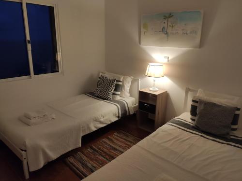 a room with two beds and a lamp and a window at Casa da Ovelha I Madeira in Fajã da Ovelha