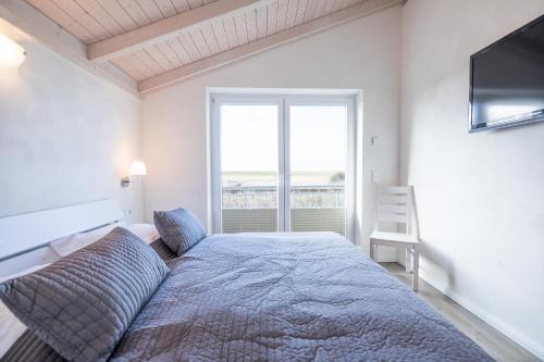 ein Schlafzimmer mit einem großen Bett und einem Fenster in der Unterkunft Ferienhaus Seestern in Dagebüll