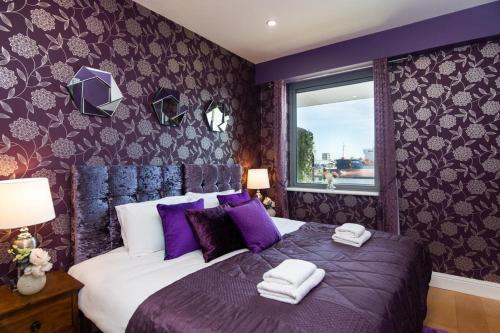 a purple bedroom with a bed with towels on it at Sea View Luxury City Centre - Best Location in Galway