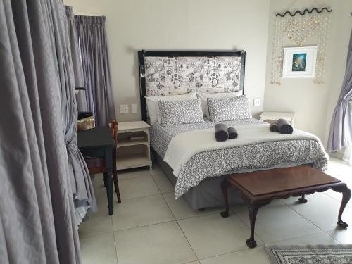 a bedroom with a large bed and a table at House Mulberry Guesthouse in Pretoria