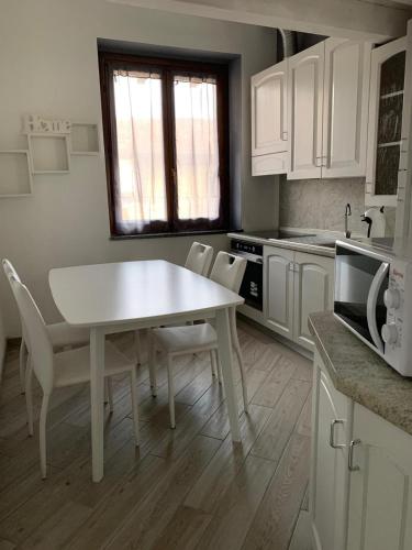een witte keuken met een witte tafel en stoelen bij APPARTAMENTO PIERANGELO DI FRONTE MALPENSA T1 e T2 in Vizzola Ticino