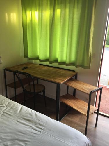 um quarto com uma mesa e uma cortina verde em Fasthotel Saint-Amand-Montrond Orval em Orval