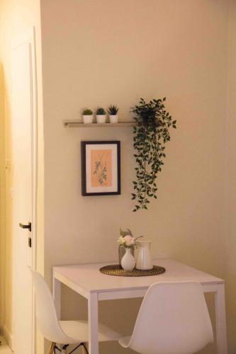 a white table with chairs and plants on a wall at Nikoletta's Studio 2 in Komotini