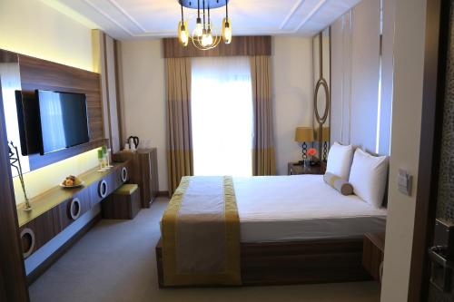 a hotel room with a bed and a television at Burçman Hotel Vişne in Yıldırım