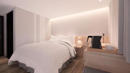 a white bedroom with a large bed and a desk at Ta Lee Hotel in Tainan