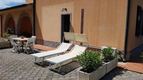 a patio with white chairs and a table and a building at Villa Mandrioli in Cecina