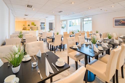 un restaurante con mesas negras y sillas blancas en Trip Inn Hotel Astoria, en Gotinga