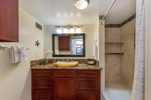 La salle de bains est pourvue d'un lavabo, d'un miroir et d'une douche. dans l'établissement Hanalei Bay Resort 6101 condo, à Princeville