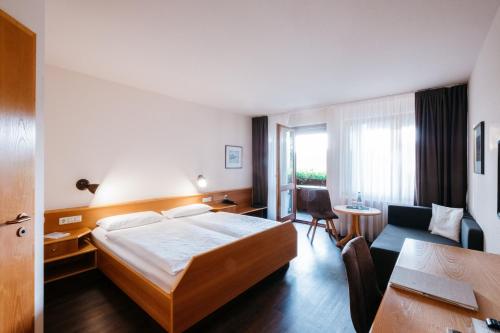 a hotel room with a bed and a desk and a couch at Restaurant & Landhotel Winter in Gomadingen