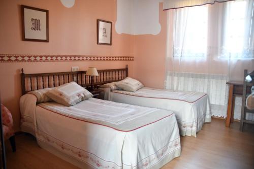 two beds in a room with a window at Casa Rural Molino Del Arriero in Luyego de Somoza