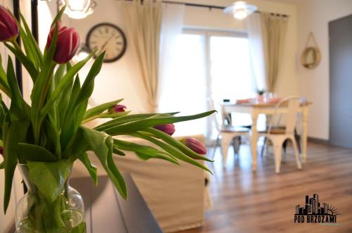 a vase filled with red tulips sitting on a counter in a room at Pod Brzozami Apartamenty 5 Mórz in Ustronie Morskie