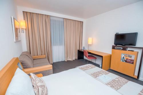 a hotel room with a bed and a desk and a television at Accra City Hotel in Accra
