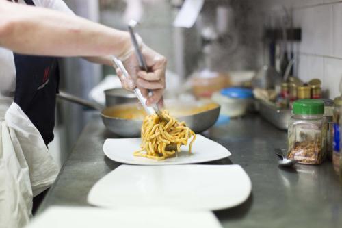 a person preparing pasta on a plate in a kitchen at Hotel Ristorante Umbria in Orvieto
