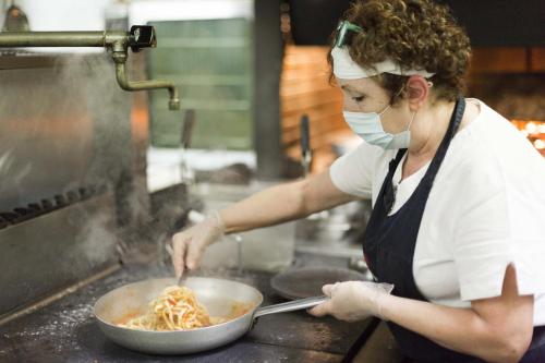 a woman in a kitchen preparing noodles in a pan at Hotel Ristorante Umbria in Orvieto