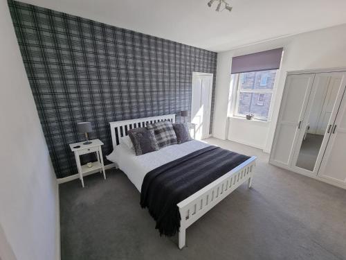 a bedroom with a white bed with a black blanket at Bespoke Tours Scotland Accommodation @ Morrison Street in Edinburgh