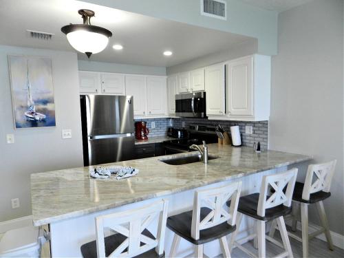 a kitchen with white cabinets and a stainless steel refrigerator at 17th Floor 1 BR Resort Condo Direct Oceanfront Wyndham Ocean Walk Resort Daytona Beach 1706 in Daytona Beach
