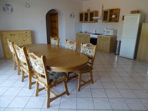 a kitchen with a wooden table with chairs and a refrigerator at Alabárdos Panzió és Apartmanház in Esztergom
