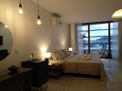 a bedroom with a bed and a table and a mirror at Orlanova Boutique Hotel in Arraial do Cabo