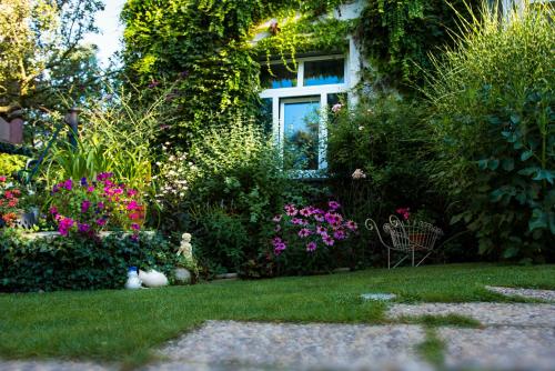 einen Garten mit Blumen und ein Haus mit einem Fenster in der Unterkunft Vila Josefina in Prag