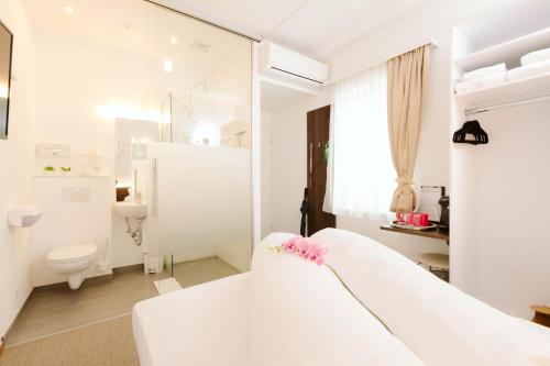 uma casa de banho branca com uma cama branca e um WC. em Velden24 - create your own stay em Velden am Wörthersee