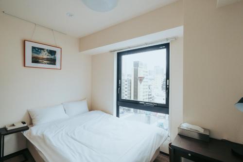 a bedroom with a white bed and a large window at unito SHIODOME in Tokyo