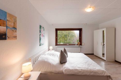 Un dormitorio con una gran cama blanca y una ventana. en Lund36, en Husum
