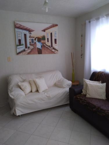 a living room with a white couch and a painting on the wall at condominio moradas de guarajuba in Guarajuba