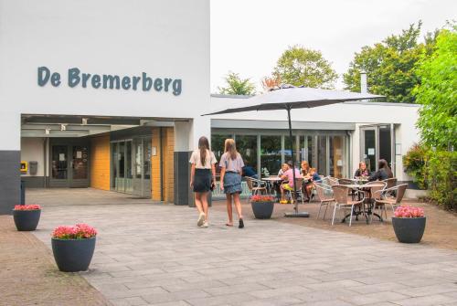 two women walking down a sidewalk in front of a building at Bungalowpark De Bremerberg in Biddinghuizen