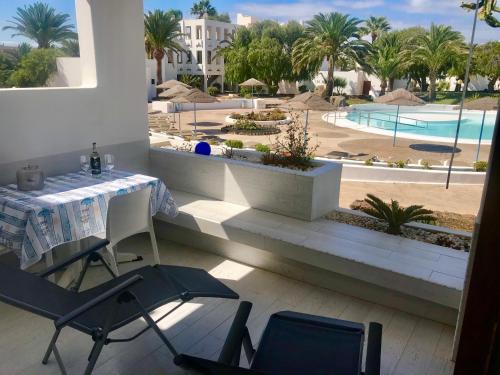 d'un balcon avec une table, des chaises et une piscine. dans l'établissement CASA ROSA, à Costa Teguise