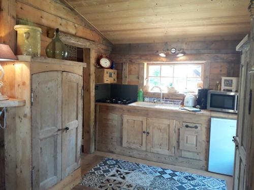 een keuken met houten kasten, een wastafel en een magnetron bij Charmant Mazot in Saint-Gervais-les-Bains