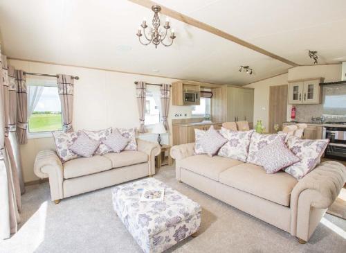a living room with two couches and a table at Newperran Holiday Park in Newquay