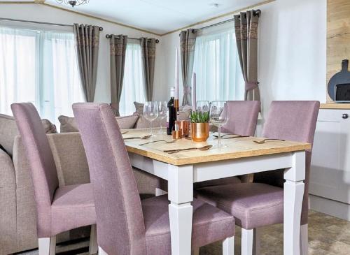 a dining room table with wine glasses and purple chairs at Newperran Holiday Park in Newquay