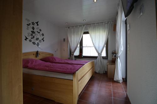 a bedroom with a bed with purple sheets and a window at Komfort Ferienwohnung FEWO74-1 in Bremm