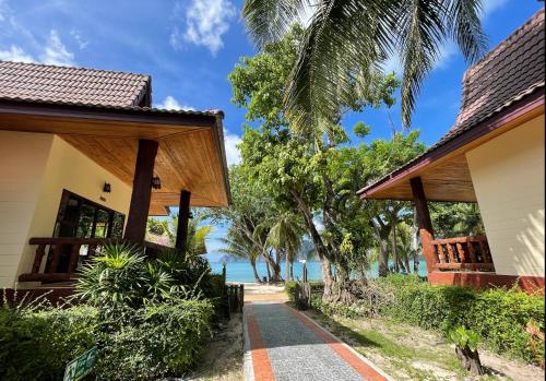 a walkway between two houses with the beach in the background at Phi Phi Villa Resort in Phi Phi Don