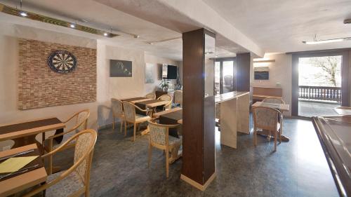 a restaurant with tables and chairs and a clock on the wall at Le Chamois in Les Diablerets
