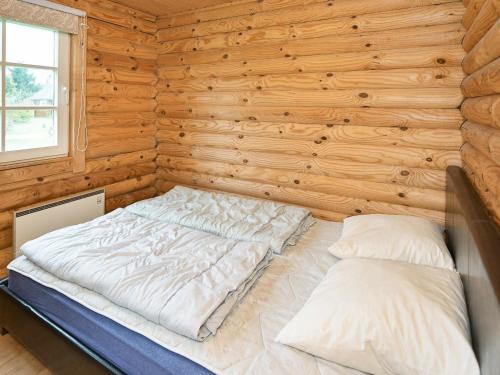 Cama en habitación de madera con 2 almohadas en Holiday Home Torpet VI, en Hovborg