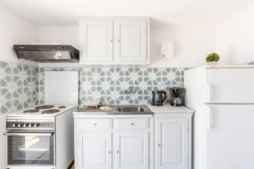 a kitchen with white cabinets and a white refrigerator at Katerina Horizon Apartments by Konnect - 1,8km from Ipsos beach in Ýpsos