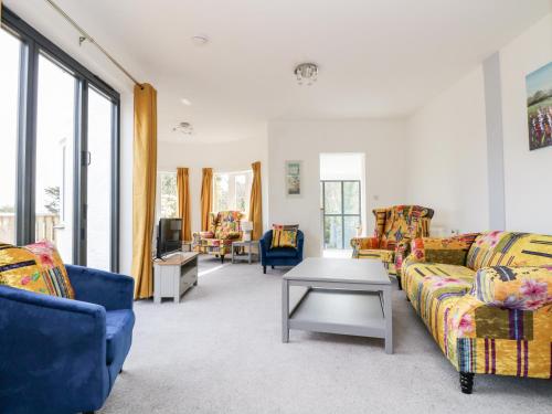 a living room with two couches and a table at Dovefields in Helston