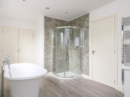 a bathroom with a shower and a white tub at Dovefields in Helston