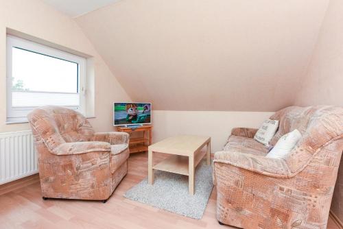 a living room with two chairs and a tv at Ferienwohnungen im Haus Trudi in Bensersiel