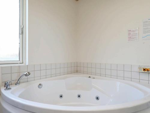 a large white tub in a bathroom with a window at 8 person holiday home in Ulfborg in Fjand Gårde