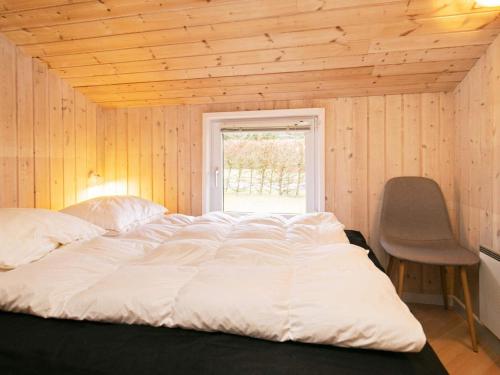 a bed in a room with a window and a chair at 10 person holiday home in Løkken-By Traum in Løkken